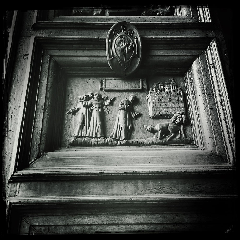 St. Francis and the Wolf of Gubbio Wood Carving on the door of the Basilica of St. Francis in Assisi Italy illustrating the story. Photo is from our Cortona Center of Photography Italy workshop